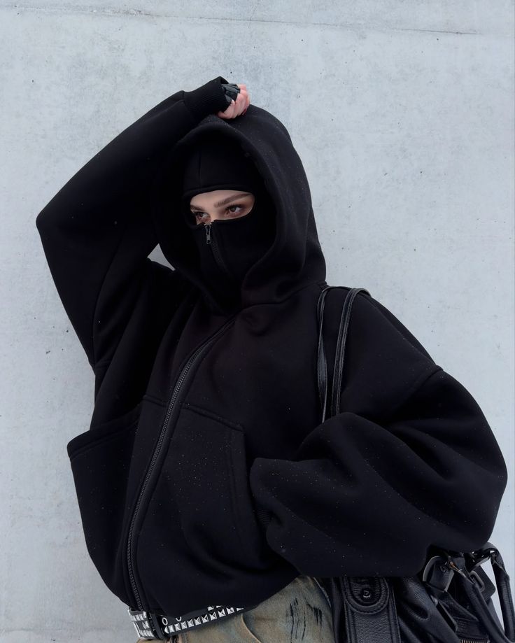 Streetwear fashion model in black balaclava hoodie, fingerless gloves, and edgy accessories, showcasing an urban ninja style.