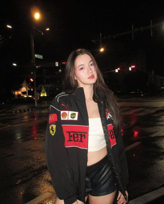 Woman wearing a black jacket with logos on a street at night