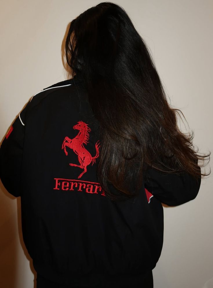 Person wearing a black Ferrari jacket with a red horse logo on the back.