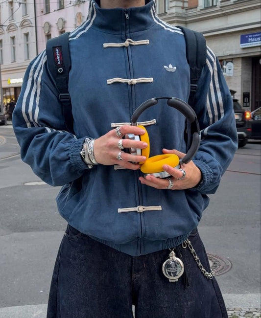 Person wearing a blue CNY jacket holding a yellow object on a city street.