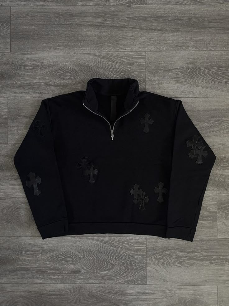 Black quarter-zip sweatshirt with cross patterns on a wooden floor