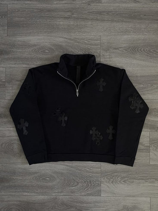 Black quarter-zip sweatshirt with cross patterns on a wooden floor