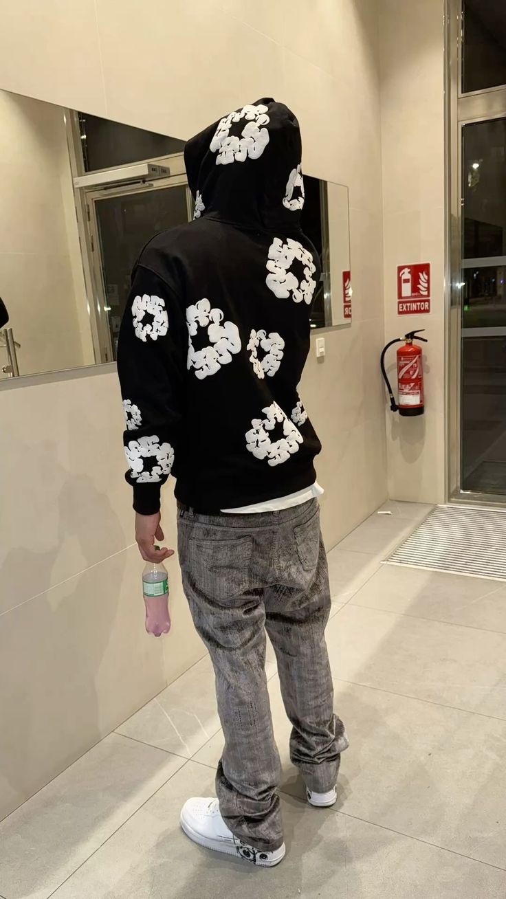 Person wearing a black hoodie with white floral patterns in an indoor setting.
