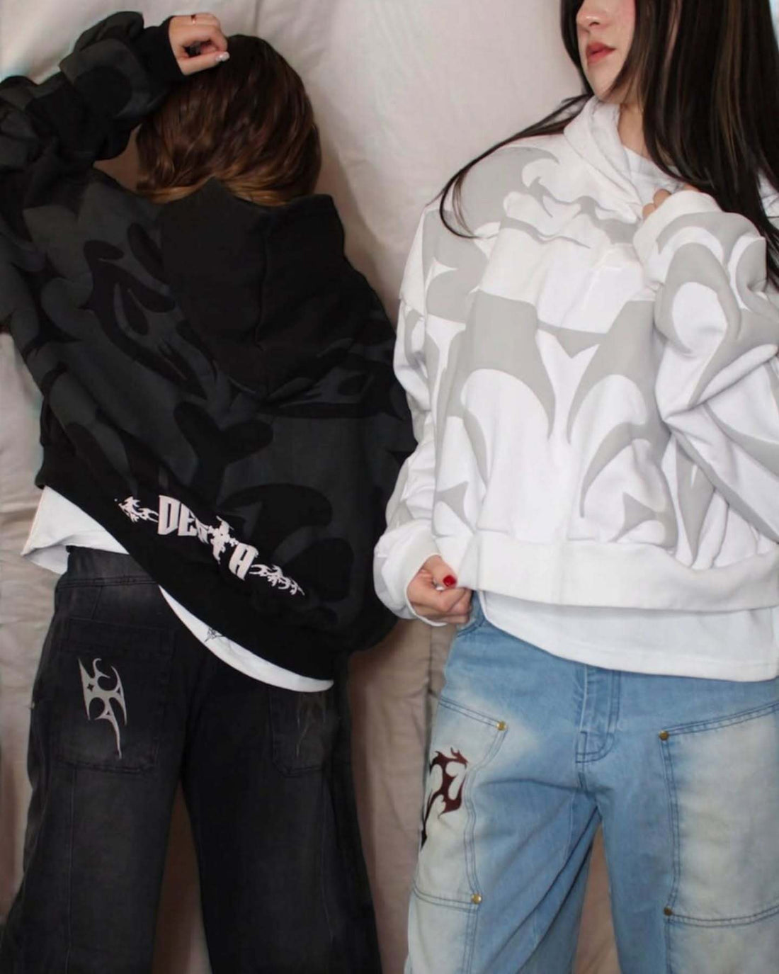 Two people wearing hoodies with graphic designs and text.