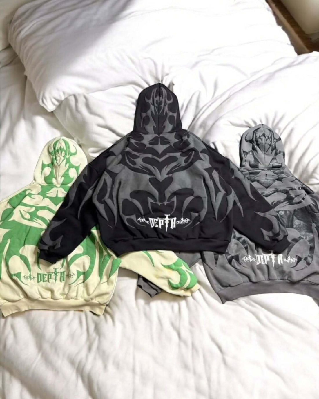 Depta Black hoodie with graphic design on a white bed