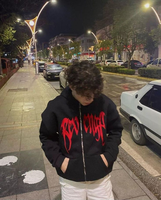 Person wearing a black Revenge Zipper hoodie on a city street at night
