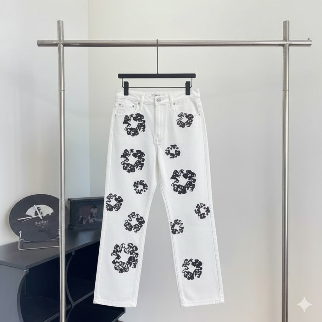 White jeans with black floral patterns hanging on a rack 