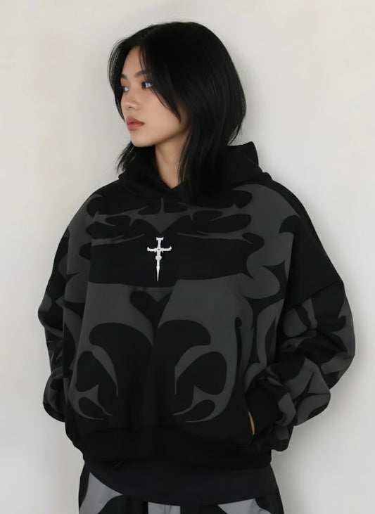 Person wearing a black Depta Y2K patterned hoodie with a white cross pendant against a white background